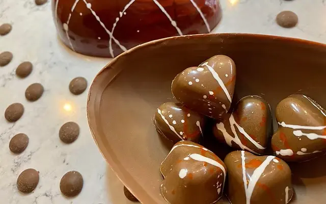 A bowl of heart-shaped local chocolates made by Castle Chocolates, beautifully handcrafted with artistic designs.