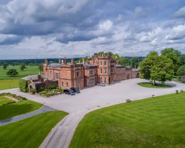 Aerial view of Netherby Hall, a luxury self-catering accommodation in Cumbria, featuring stunning architecture, manicured gardens, and expansive countryside. Ideal for a tranquil getaway, with dog-friendly options and close proximity to scenic attractions like Hadrian's Wall and the Lake District.