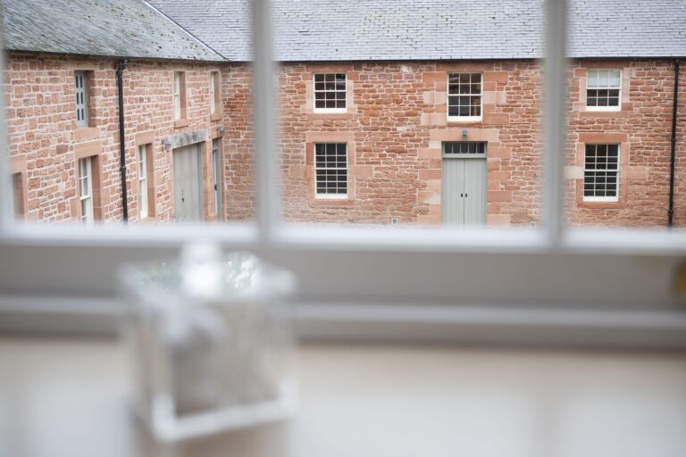 View from a window of the Clock Tower Apartment looking out onto the historic stone buildings at Netherby Hall