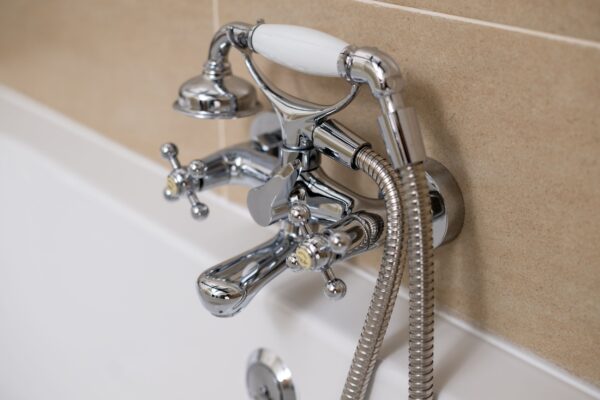 Chrome traditional style bathtub taps and handheld shower attachment in the Clock Tower Apartment at Netherby Hall