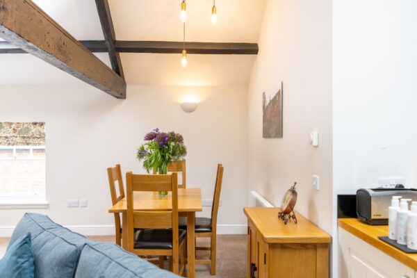 Interior of the Clock Tower Apartment at Netherby Hall, featuring a wooden dining set and luxury self-catering accommodation in Cumbria
