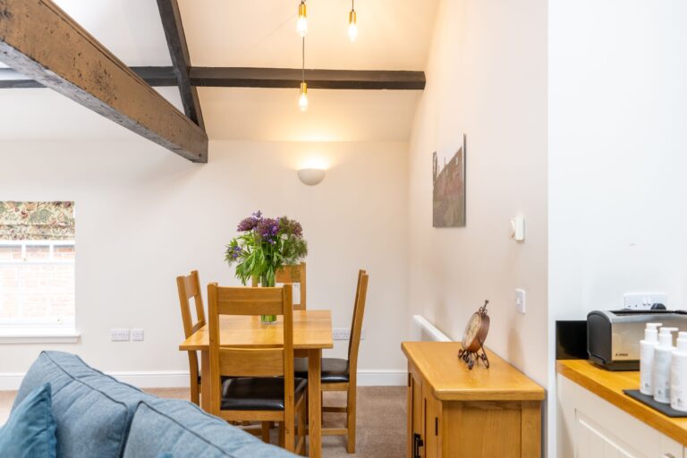 Interior of the Clock Tower Apartment at Netherby Hall, featuring a wooden dining set and luxury self-catering accommodation in Cumbria