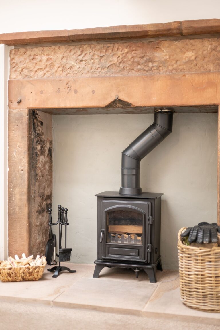 Modern wood burning stove in the rustic stone fireplace of the Clock Tower Apartment at Netherby Hall, luxury self-catering Cumbria accommodation