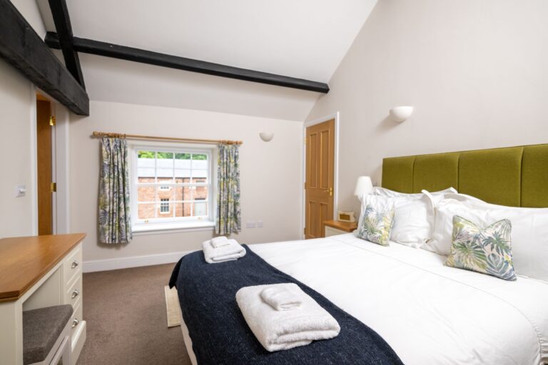 Luxury double bedroom in the Clock Tower Apartment at Netherby Hall, featuring a large bed and traditional wooden beams