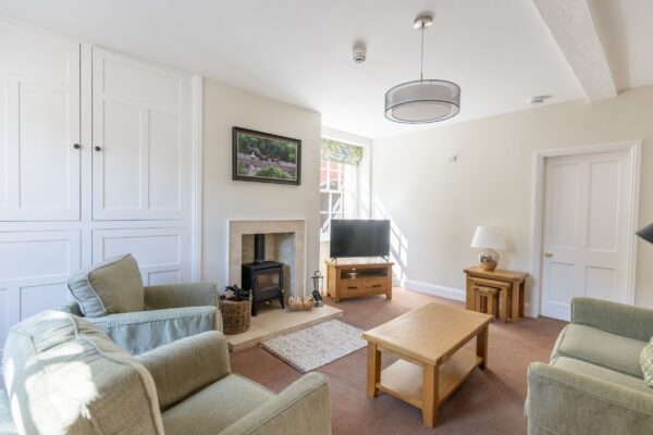 Luxury living room interior of the Coach House self-catering apartment at Netherby Hall, Cumbria, featuring a wood-burning stove and soft furnishings