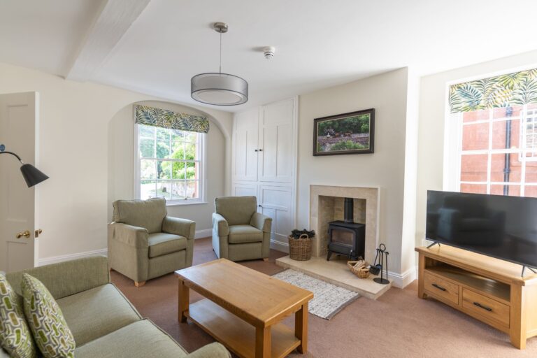Living room of the Coach House luxury self-catering apartment at Netherby Hall, Cumbria, featuring a wood-burning stove and comfortable seating