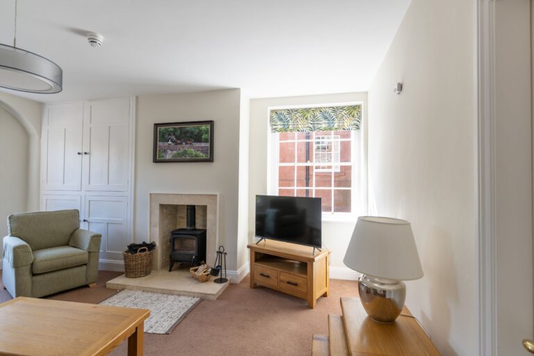 Modern living room in the Coach House luxury self-catering apartment at Netherby Hall, featuring a wood-burning stove and cozy furnishings