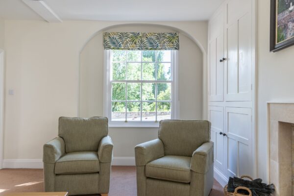 Luxury living room with two grey armchairs and a window view in the Coach House self-catering apartment at Netherby Hall, Cumbria