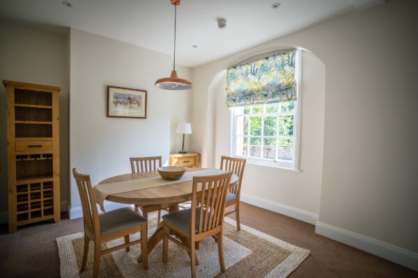 Dining area in the Coach House luxury self-catering apartment at Netherby Hall, Cumbria, featuring an oval wooden table and chairs
