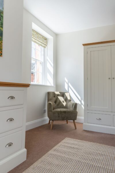 Cozy armchair by a window in a bright, modern bedroom at Coach House self-catering apartment, Netherby Hall