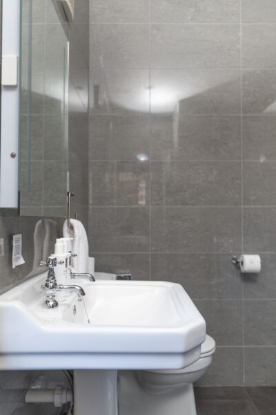 White ceramic pedestal sink and toilet in the luxury Coach House apartment at Netherby Hall, Cumbria