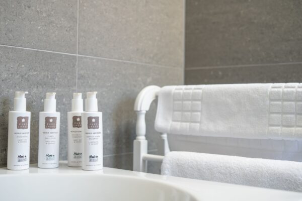 Luxury toiletries and white towels in a bathroom at the Coach House apartment, Netherby Hall