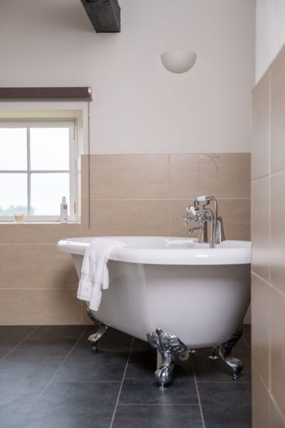 White clawfoot bathtub with chrome fixtures and a white towel in the Engineer Apartment at Netherby Hall, Cumbria