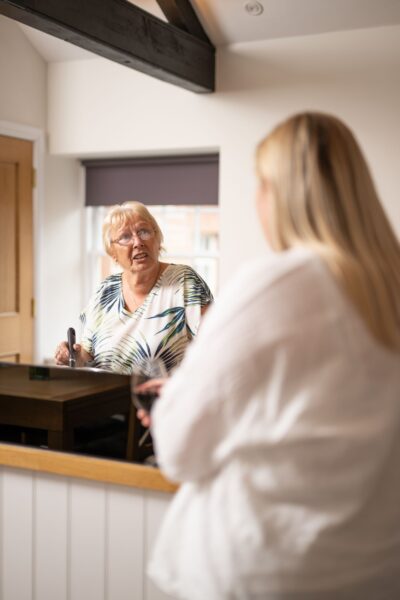 A woman looking into a mirror in the well-appointed Engineer Apartment at Netherby Hall, Cumbria