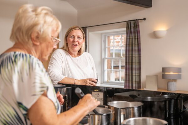 Two women enjoying drinks in the kitchen of the Engineer Apartment at Netherby Hall, luxury self-catering accommodation in Cumbria