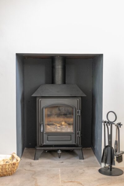 Black wood-burning stove in a modern fireplace at the luxury Gardener's Cottage self-catering accommodation in Cumbria