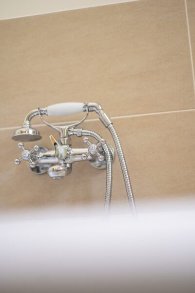 Chrome vintage-style bathtub faucet and handheld shower attachment in the Gardener's Cottage luxury self-catering apartment