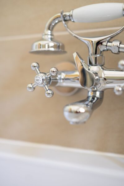 Chrome vintage-style bath faucet and shower fixture in the luxurious Gardener's Cottage at Netherby Hall, Cumbria
