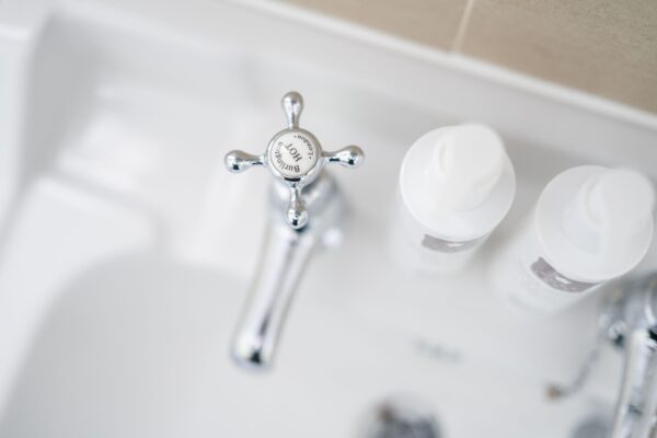 Close-up view of a chrome crosshead tap and toiletries in the luxury Gardener's Cottage at Netherby Hall, Cumbria