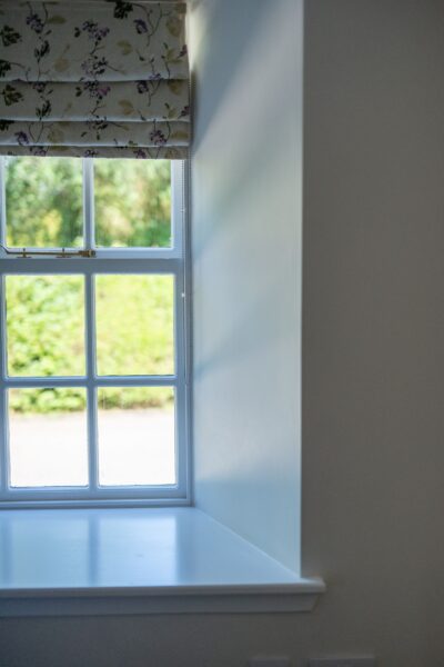 View through a window with floral Roman blinds at the Gardener's Cottage, a luxury self-catering apartment at Netherby Hall in Cumbria