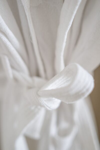 Close-up of a white plush bathrobe tied with a belt at the Gardener's Cottage apartment in Netherby Hall