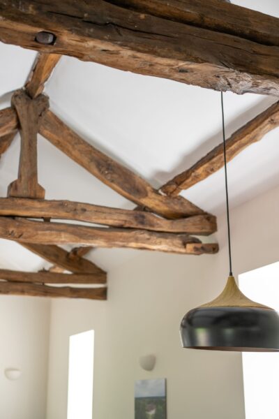 Rustic exposed wooden ceiling beams and a modern pendant light in the Gardener's Cottage at Netherby Hall, Cumbria