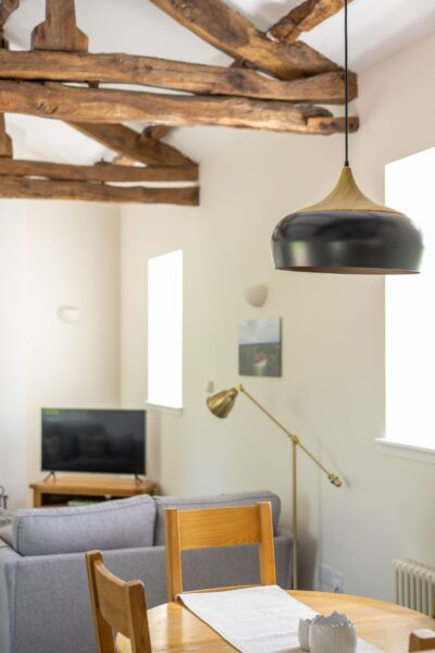 Interior view of the living and dining area in Gardener's Cottage, featuring rustic wooden ceiling beams and modern decor at Netherby Hall