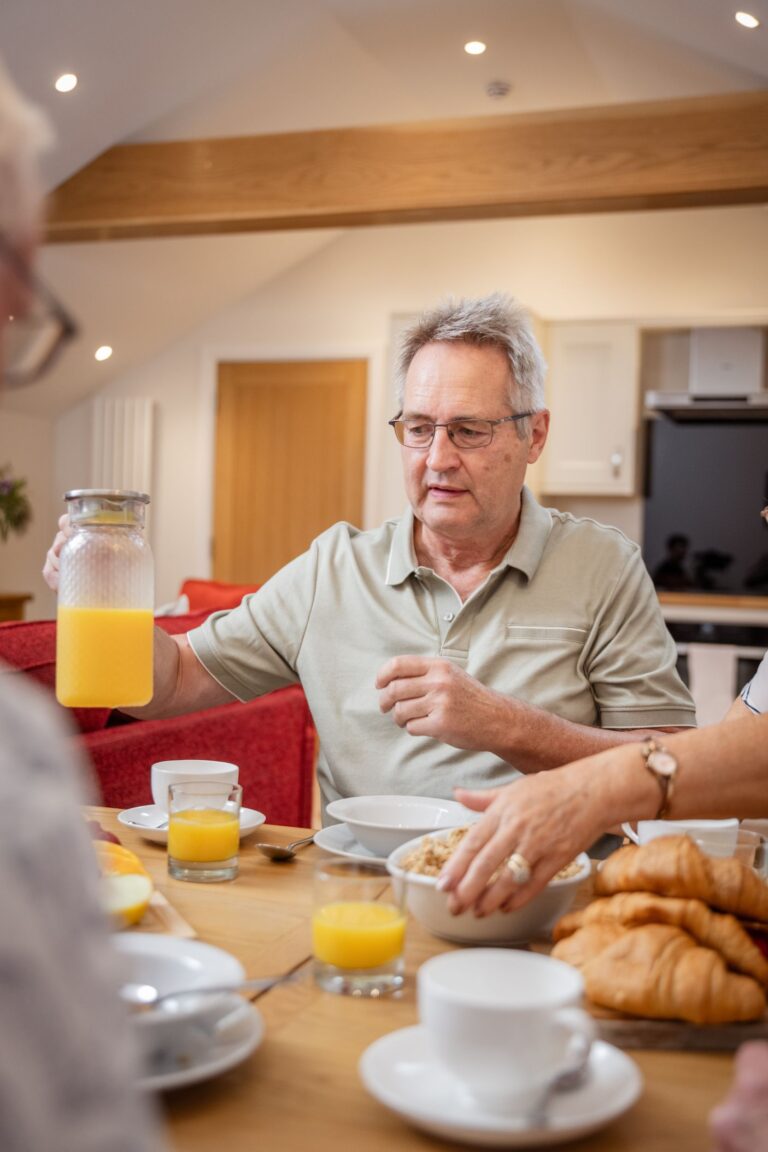 Guests enjoying a breakfast spread with orange juice and croissants in the Grooms' Quarters apartment at Netherby Hall, Cumbria