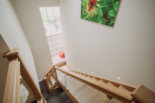 Modern wooden staircase with glass balustrade and bright window in the Grooms' Quarters luxury self-catering apartment at Netherby Hall