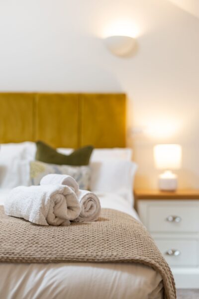 Fresh white towels on a bed in the luxury Grooms' Quarters apartment at Netherby Hall, Cumbria