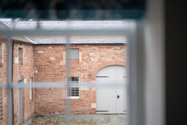 View of the historic stone courtyard and exterior of Grooms' Quarters at Netherby Hall, luxury self-catering accommodation in Cumbria