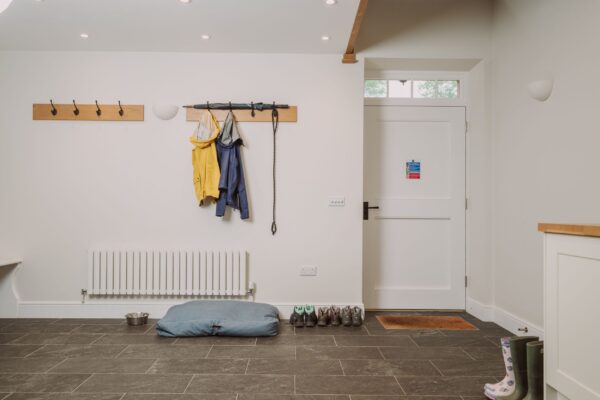 Mudroom in the dog-friendly Grooms' Quarters apartment at Netherby Hall, featuring coat hooks, a radiator, and a pet bed