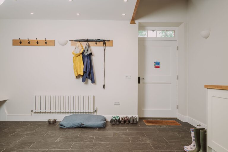 Mudroom in the dog-friendly Grooms' Quarters apartment at Netherby Hall, featuring coat hooks, a radiator, and a pet bed