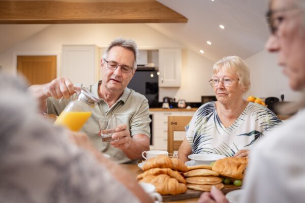 Group of seniors enjoying a breakfast of croissants and pancakes in the luxury Grooms' Quarters apartment at Netherby Hall
