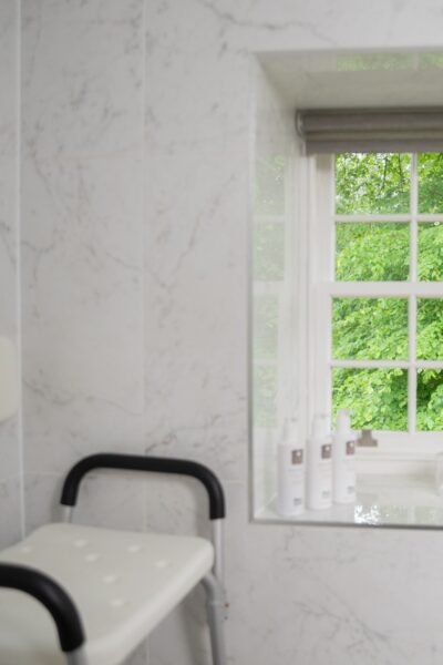 Bathroom interior of Independent Apartment featuring marble walls and a window view of lush greenery at Netherby Hall