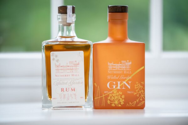 Two bottles of Netherby Hall Walled Garden Rum and Gin sitting on a windowsill in the Independent Apartment