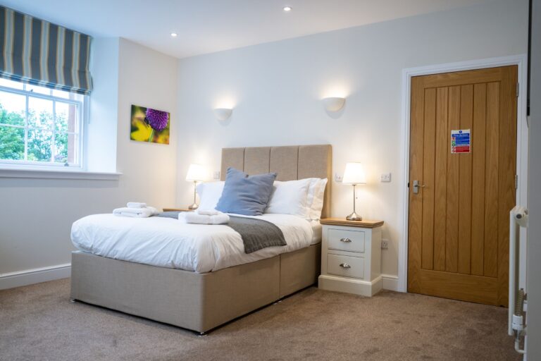 Modern bedroom in Independent Apartment at Netherby Hall, featuring a double bed with white linens and bedside lamps