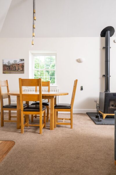 Dining area in the Independent Apartment at Netherby Hall featuring a wooden table and chairs near a wood-burning stove