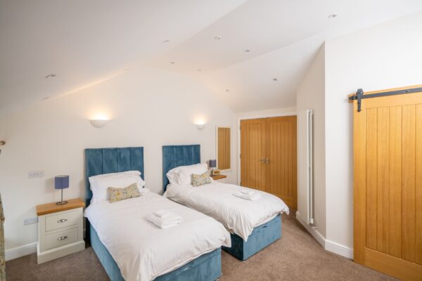 Twin beds with blue velvet headboards in the Independent Apartment at Netherby Hall, Cumbria