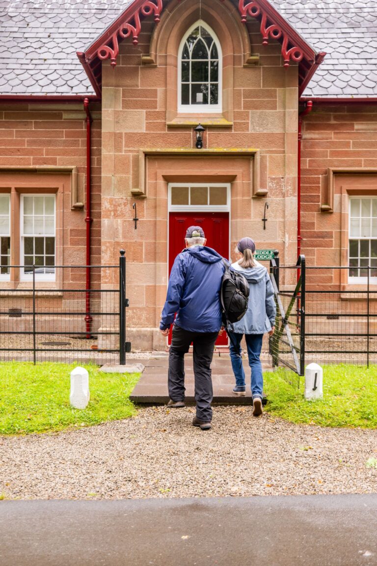 Two guests walking towards the entrance of Middle Lodge, a luxury self-catering apartment at Netherby Hall in Cumbria