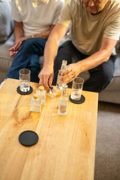 A man pouring drinks from a bottle into glasses on a wooden coffee table at Middle Lodge, luxury self-catering accommodation in Cumbria