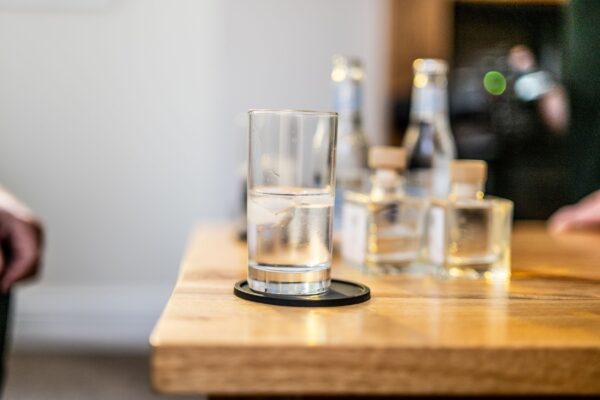 Glass of water and bottles on a wooden table in the Middle Lodge luxury self-catering apartment at Netherby Hall