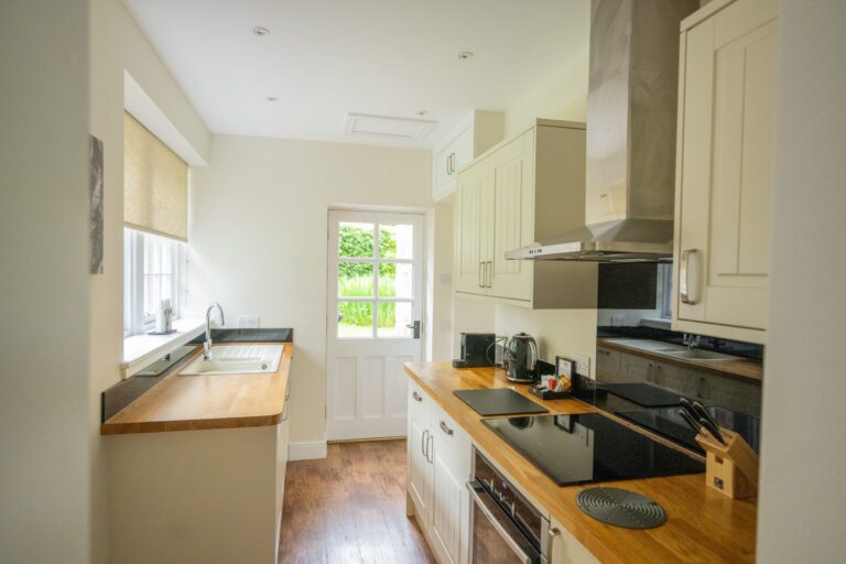 Modern kitchen in Middle Lodge self-catering apartment at Netherby Hall, featuring wooden countertops and sleek cream cabinetry