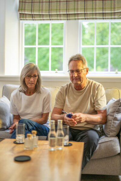 An older couple sitting on a sofa in a bright living room at Middle Lodge, luxury self-catering accommodation in Cumbria