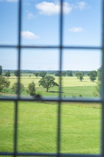 View of lush green rolling hills and trees through a window at Salutation Apartment, Netherby Hall luxury self-catering Cumbria accommodation