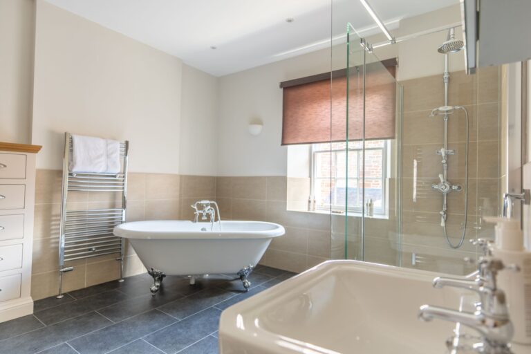 Modern bathroom in Salutation Apartment featuring a white clawfoot bathtub and walk-in glass shower at Netherby Hall, Cumbria