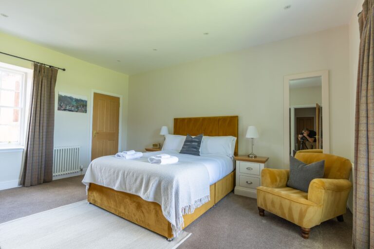 Bedroom in the luxury Salutation Apartment at Netherby Hall, featuring a mustard velvet bed and armchair