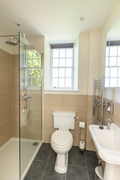 Modern bathroom in Salutation Apartment at Netherby Hall featuring a glass shower cubicle, white toilet, and sink