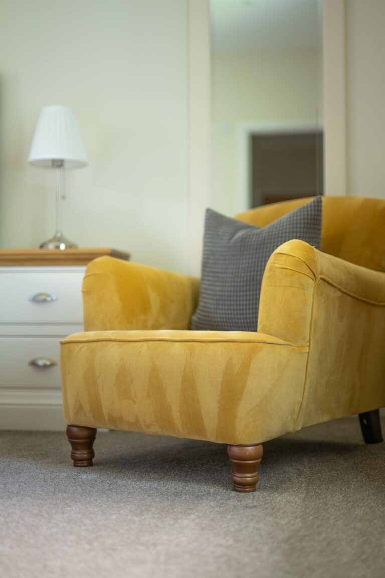 Yellow velvet armchair with a grey checkered cushion in a luxury Salutation Apartment at Netherby Hall, Cumbria