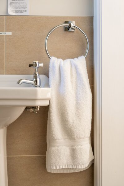 White towel hanging on a silver ring holder next to a white ceramic sink in the Salutation Apartment at Netherby Hall